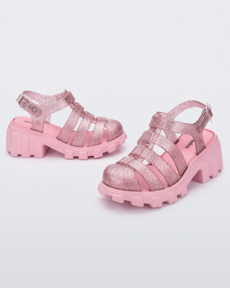 Side and angled view of a pair of glitter pink Megan kids heel sandals.