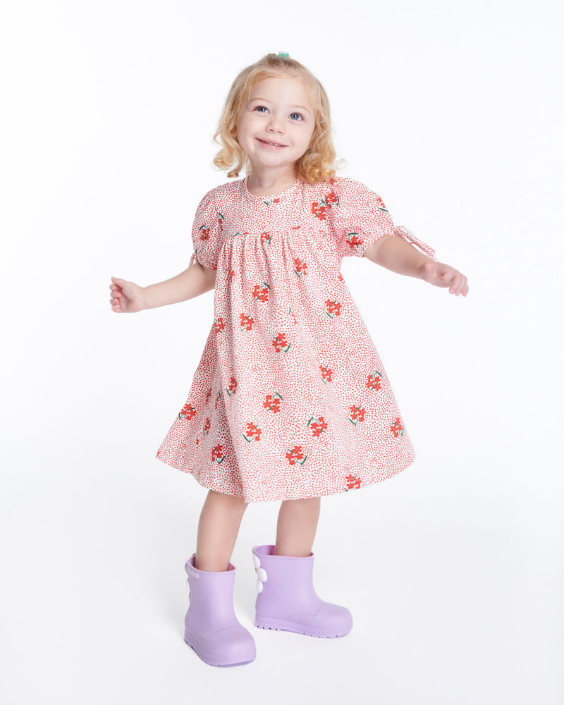 Child model in a red with flowers dress wearing a pair of lilac Welly Bloomy boots with white daisy on back