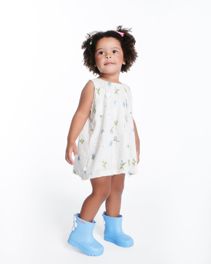 Child model in a blue with flowers dress wearing a pair of blue Welly Bloomy boots with white daisy on back