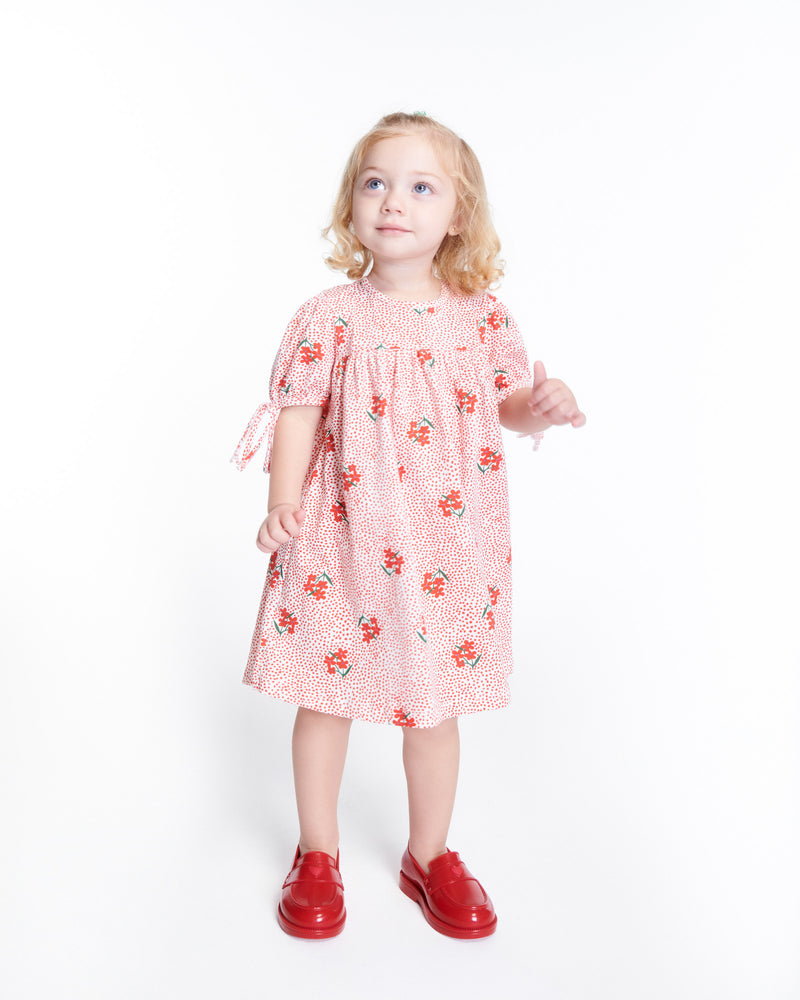 Child model in a red patterned dress wearing a pair of red Royal Love baby loafers