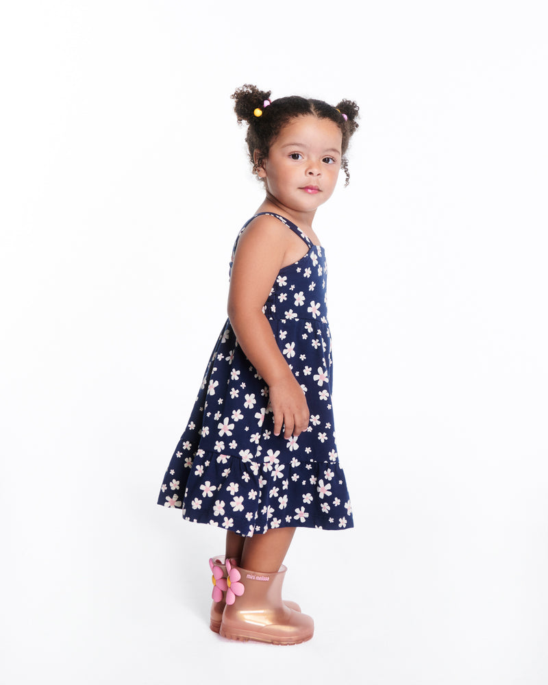Child model in a blue with flowers dress wearing a pair of pearly pink Welly Bloomy boots with pink daisy on back