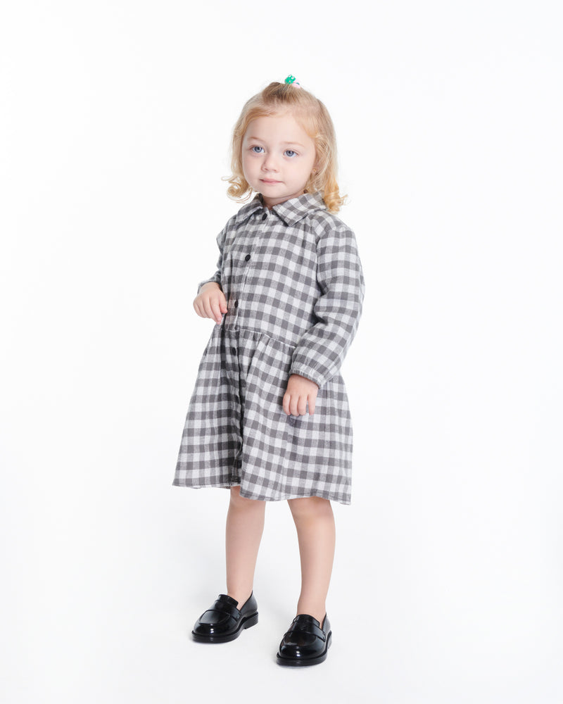 Child model in a black patterned dress wearing a pair of black Royal Love baby loafers