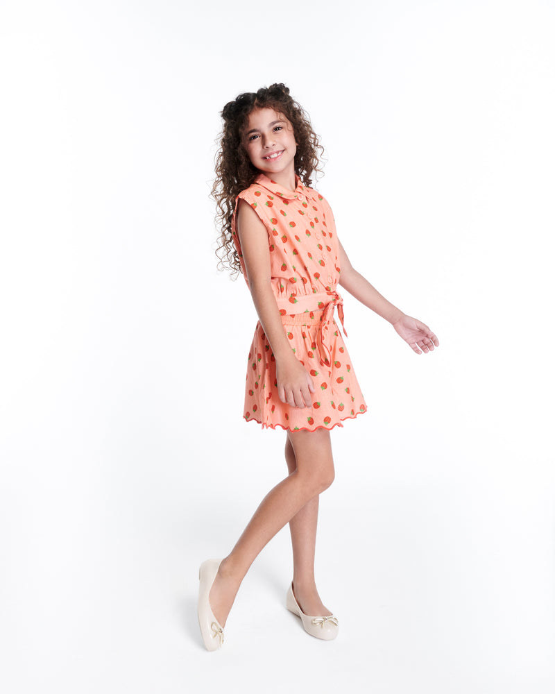 Child model in a peach dress wearing a pair of beige Sweet Love Chrome kids flats with metallic gold bow
