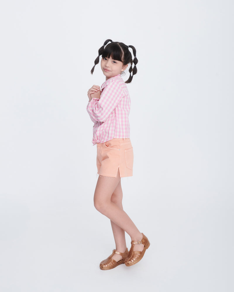 Child model in peach shorts and pink shirt wearing a pair of glitter gold Aranha 79 kids flats with buckle