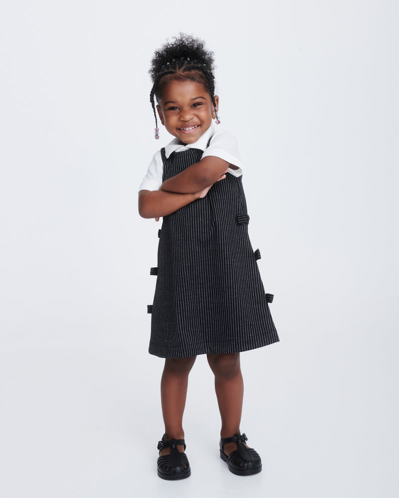 Child model in a black dress wearing a pair of black Aranha 79 baby flats with buckle