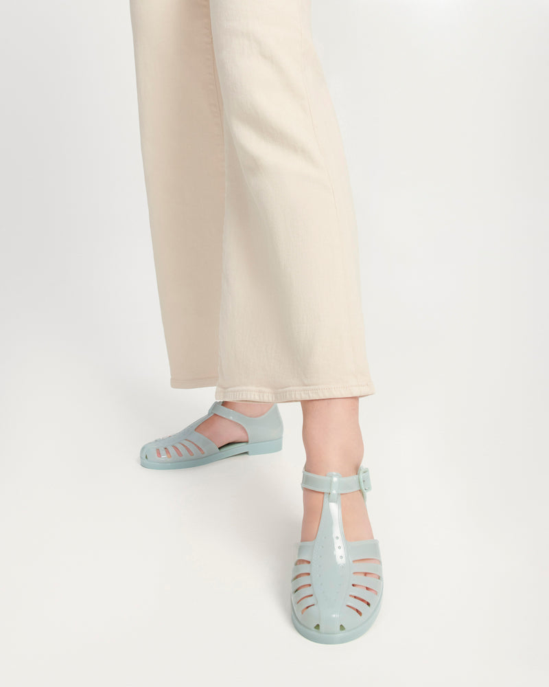 Model's legs wearing a pair of milky green Aranha 79 flats with buckle
