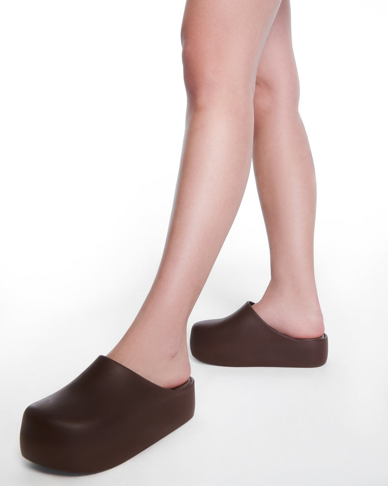 Model's legs wearing a pair of brown Free Clog Up Platforms