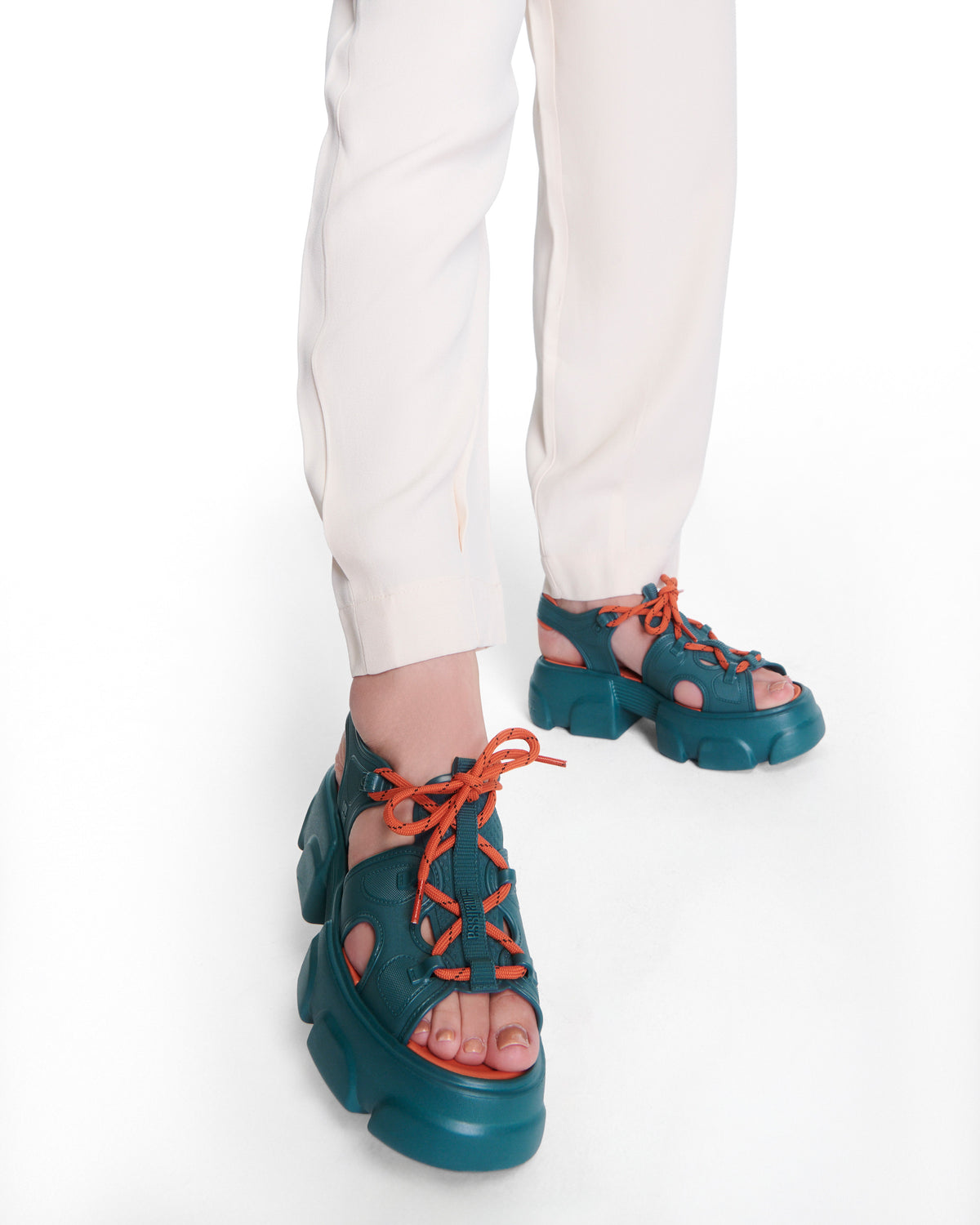 Model's legs wearing a pair of blue Camp platform sandals with orange laces and accents