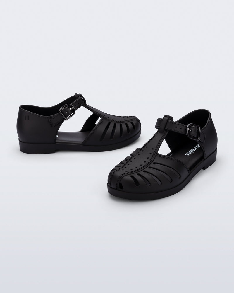 Side and angled view of a pair of black Aranha 79 kids flats with buckle