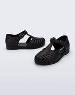 Side and angled view of a pair of black Aranha 79 kids flats with buckle