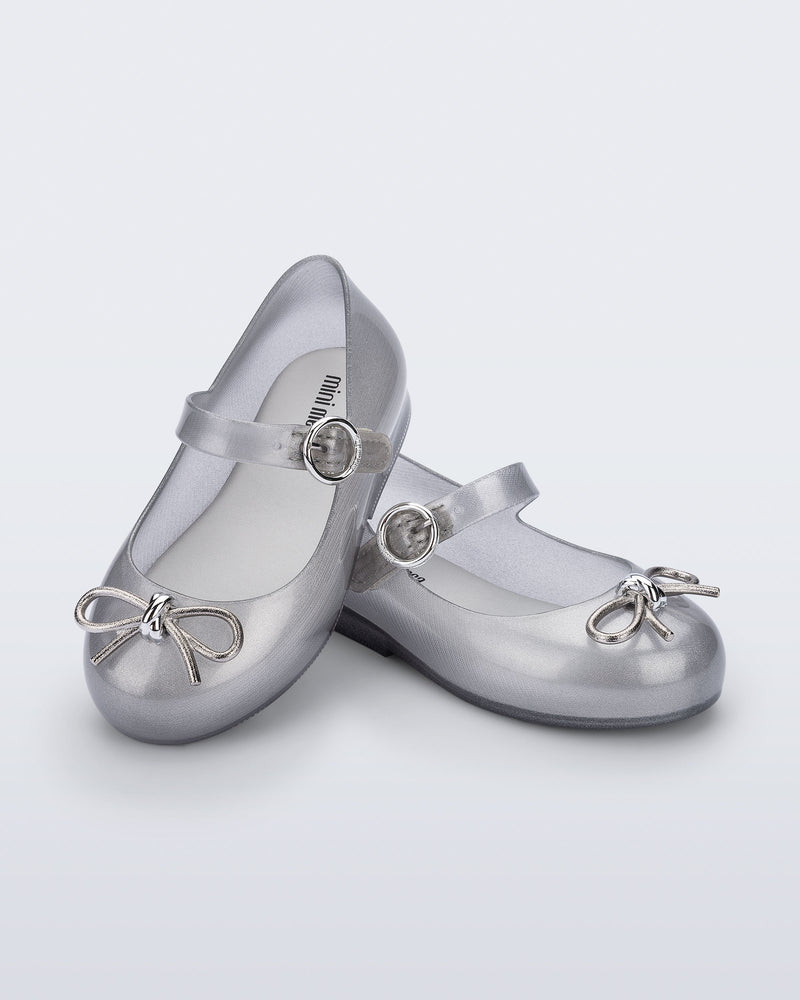 Angled view of a pair of Silver Sweet Love Chrome baby flats with metallic silver bow and buckle