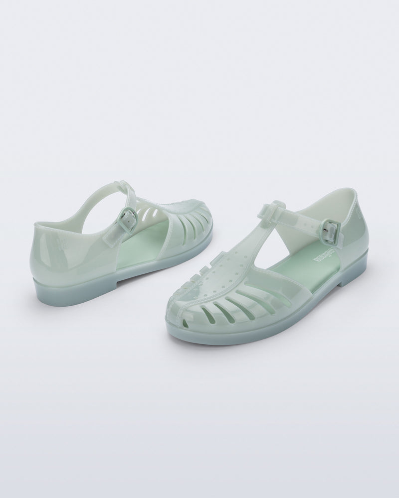Back and angled view of a pair of milky green Aranha 79 flats with buckle