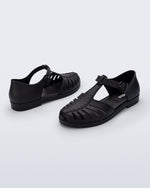 Back and angled view of a pair of black Aranha 79 flats with buckle
