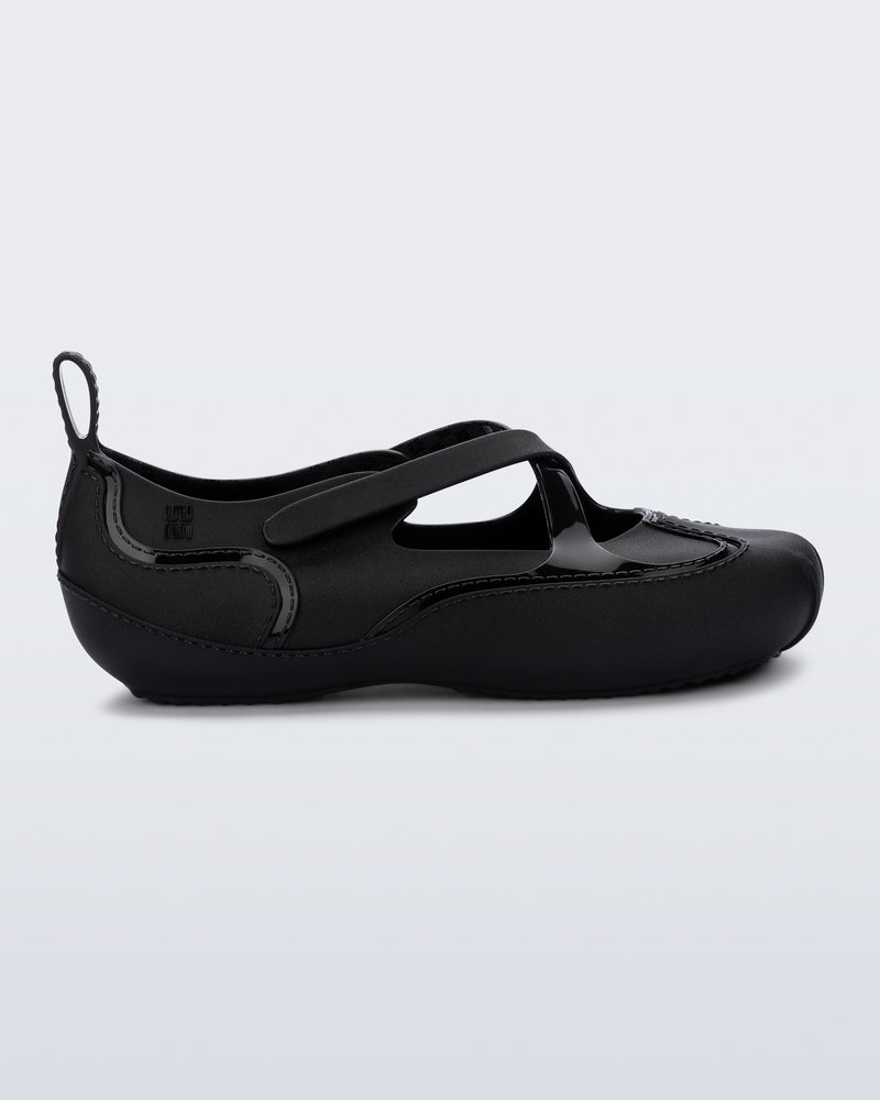 Side view of a black Aira flat with top straps