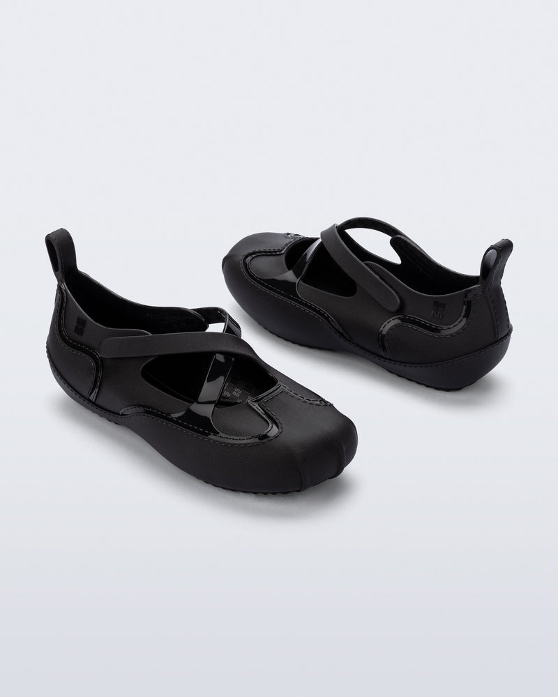Back and angled view of a pair of black Aira flats with top straps
