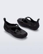 Back and angled view of a pair of black Aira flats with top straps
