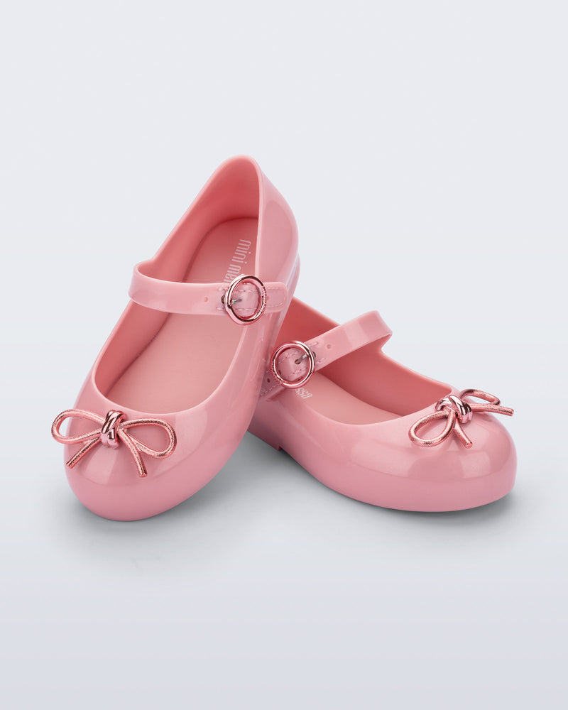 Angled view of a pair of pink Sweet Love Chrome baby flats with metallic pink bow and buckle