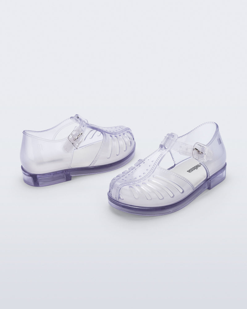 Side and angled view of a pair of clear Aranha 79 baby flats with buckle