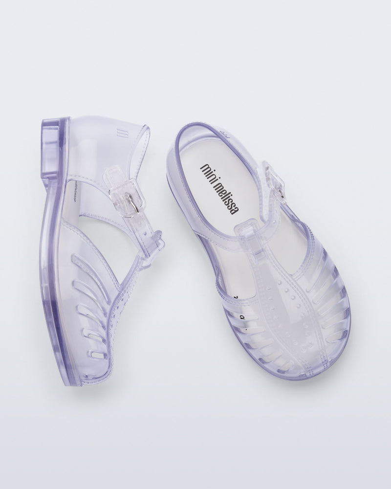 Side and top view of a pair of clear Aranha 79 baby flats with buckle