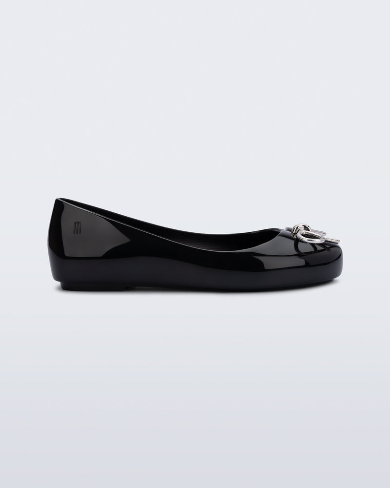 Side view of a black Sweet Love Chrome kids flat with metallic silver bow