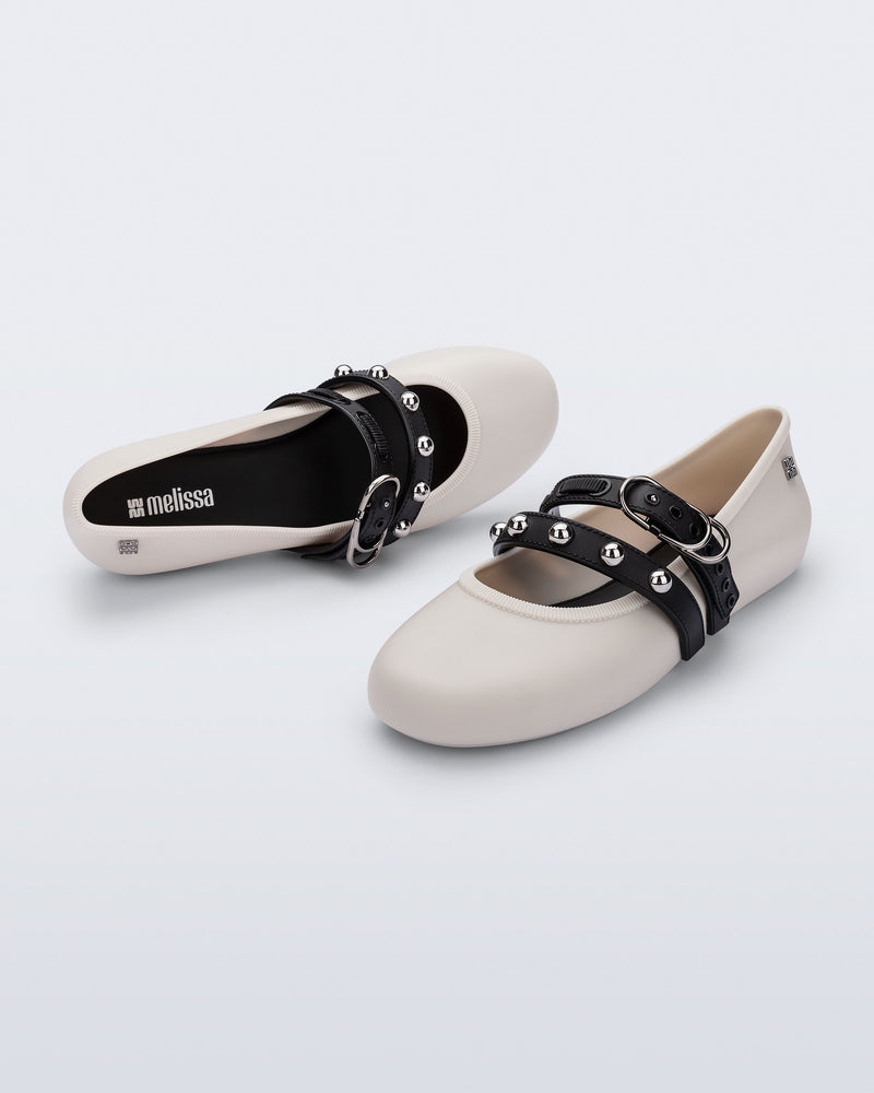 Top and angled view of a pair of beige Soft Ballerina Studs flats with black straps and silver embellishments