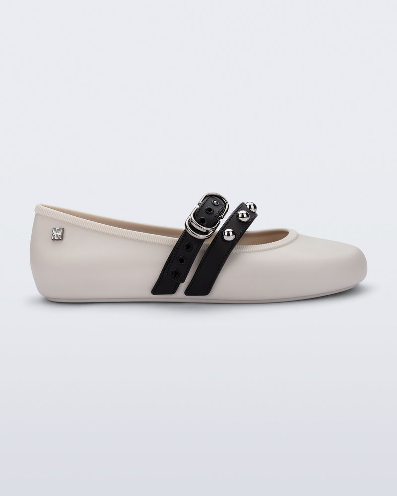 Side view of a beige Soft Ballerina Studs flat with black straps and silver embellishments