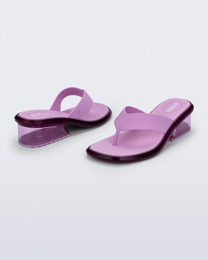 Back and angled view of a pair of pink Margot flip flops with clear pink low heel