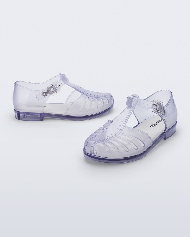 Side and angled view of a pair of clear Aranha 79 kids flats with buckle