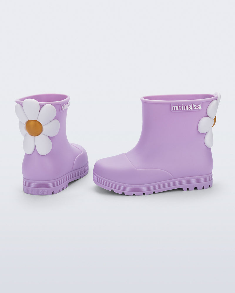 Side and back view of a pair of lilac Welly Bloomy boots with white daisy on back