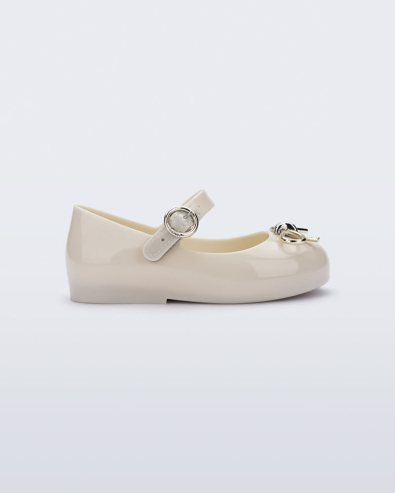 Side view of a beige Sweet Love Chrome baby flat with metallic gold bow and buckle