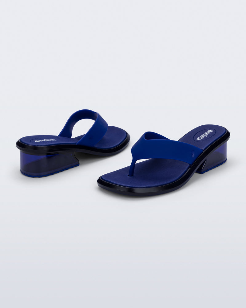 Back and angled view of a pair of blue Margot flip flops with clear blue low heel