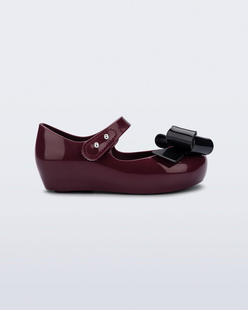 Side view of a burgundy Ultragirl Classy baby flat with black bow