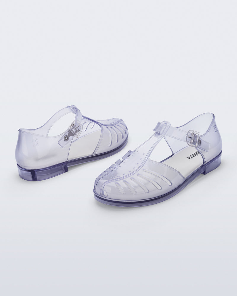 Back and angled view of a pair of clear Aranha 79 flats with buckle