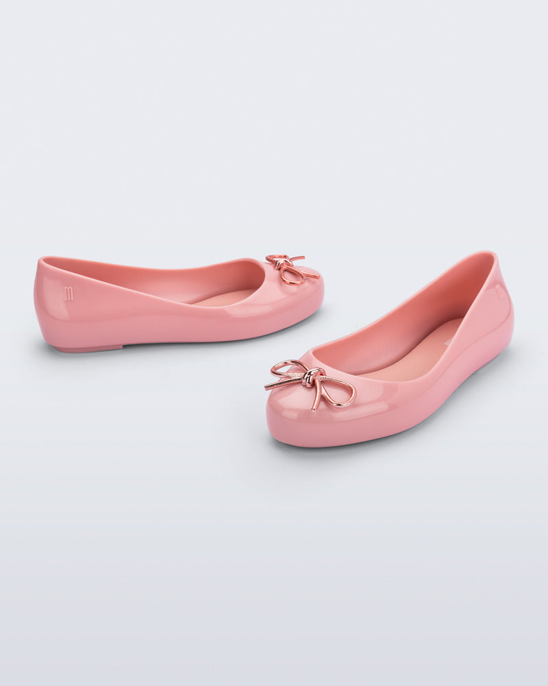 Side and angled view of a pair of pink Sweet Love Chrome kids flats with metallic pink bow