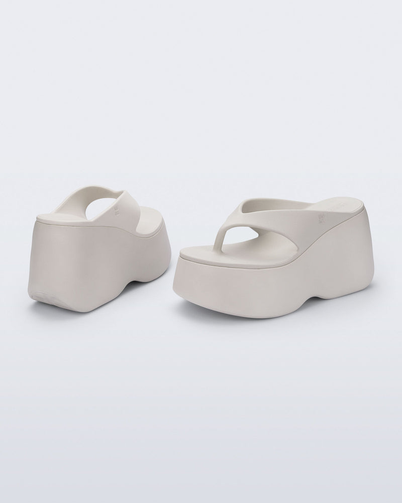 Back and angled view of a pair of beige Free Thong Wedge Platform heels