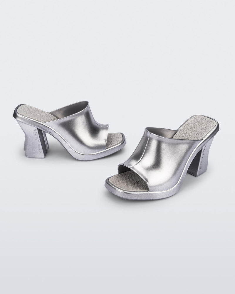 Side and angled view of a pair of silver Mule + Marc Jacobs heels.