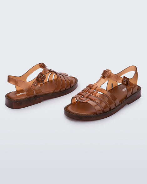 Angled view of a pair of transparent brown Possession Fresh fisherman style sandals with open toe.
