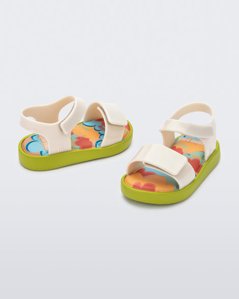 Angled view of a pair of beige baby Jump sandals with green sole