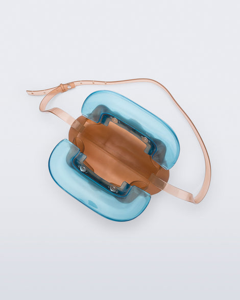 Top view of a small clear orange bag with blue clutch and long strap