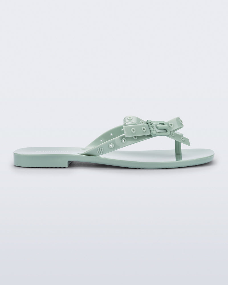 Side view of a green Harmonic Squared flip flop with bow on strap