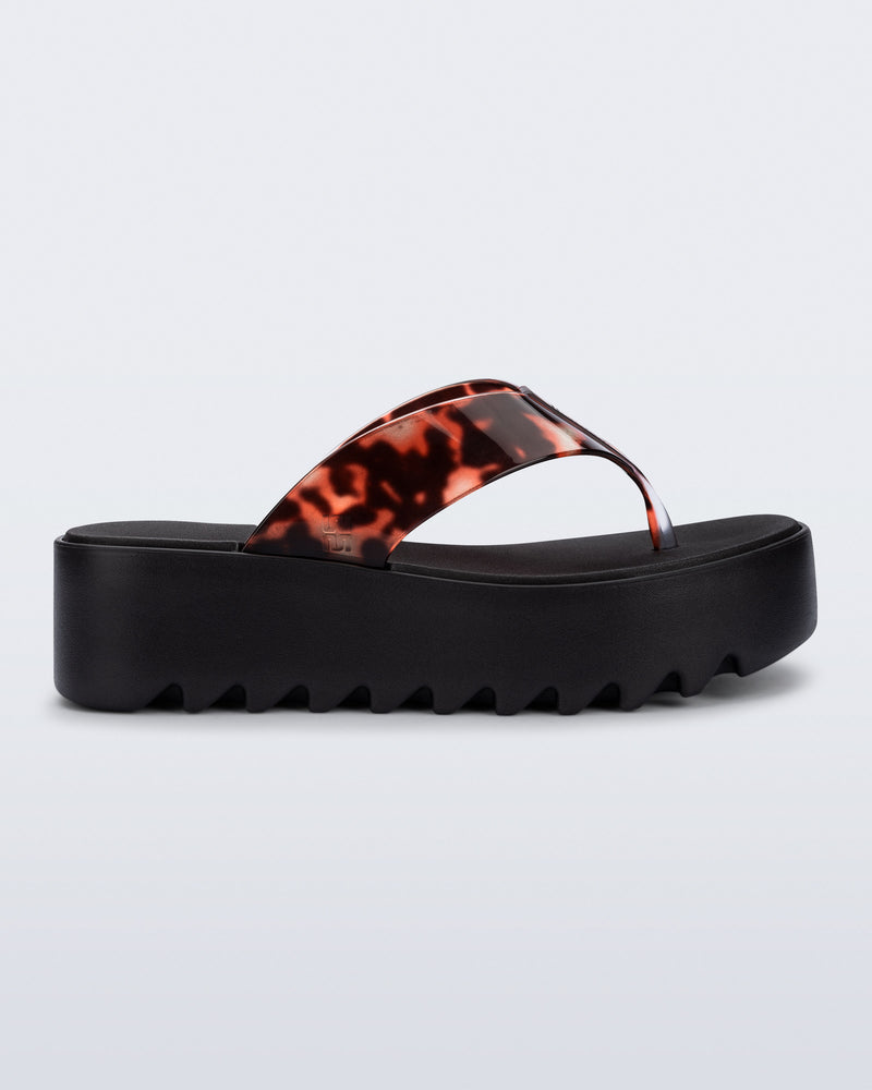 Side view of a black Thong Platform flip flop with tortoise colored strap
