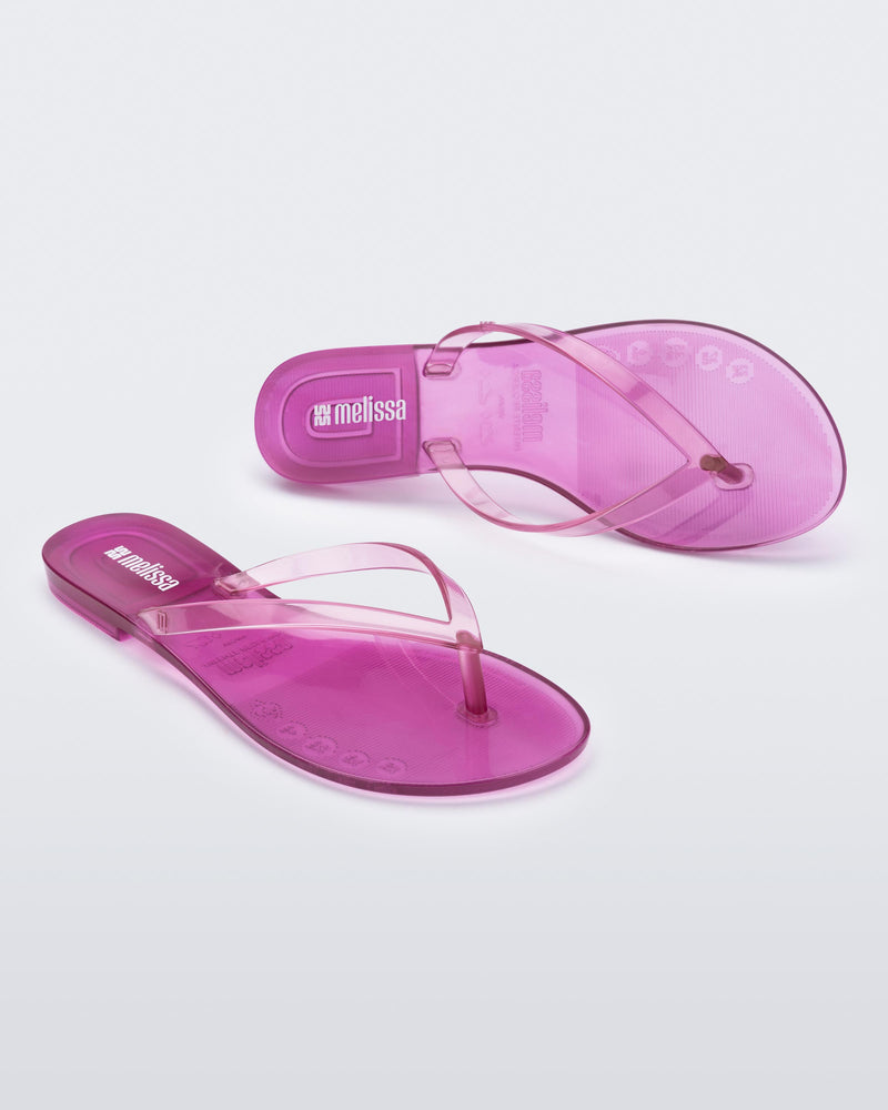 Angled and top view of a pair of clear lilac Harmonic Jelly flip flops