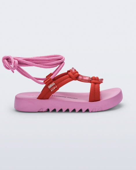 Side view of an pink sole, red upper, and pink ankle strap Kirk + Alexandre Pavao sandal