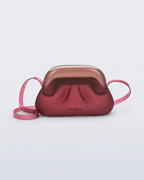 Front view of a small red bag with clear brown clutch and long strap