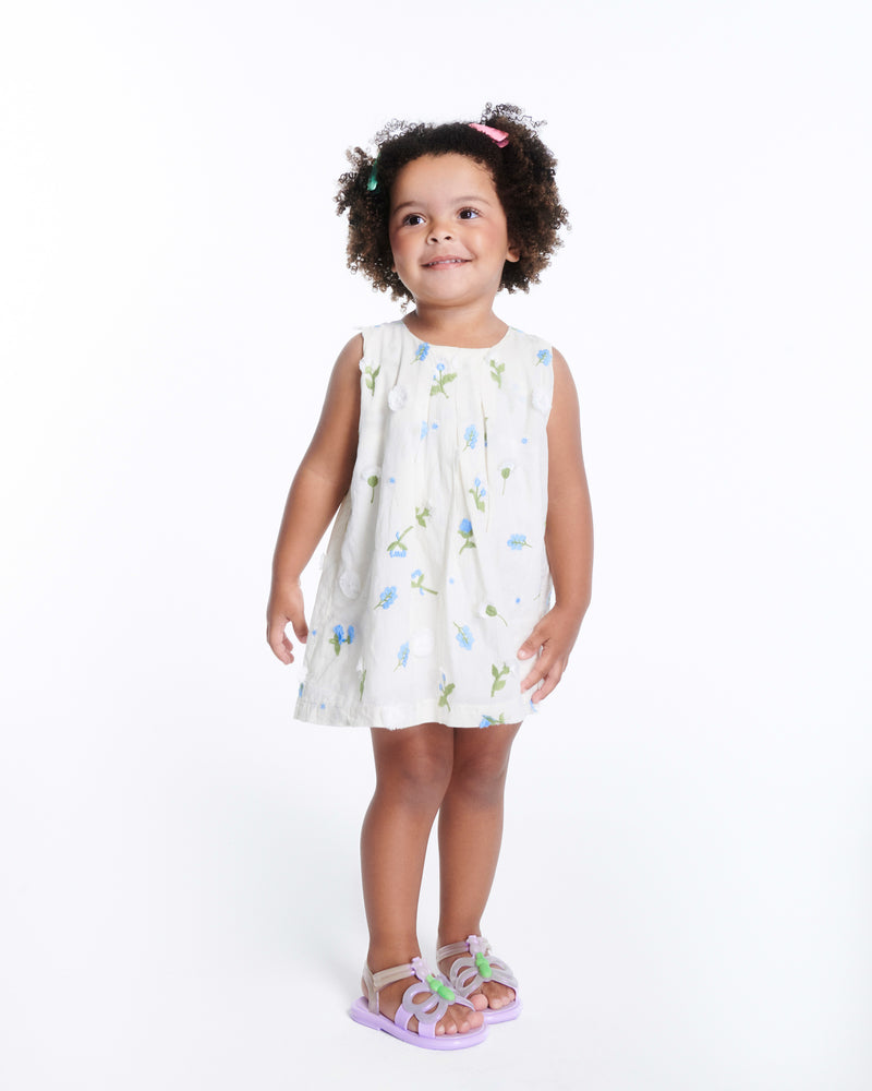 Child model in a white dress wearing a pair of lilac Hip Butterfly baby sandals