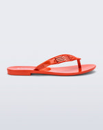 Side view of a red Harmonic M Chic flip flop
