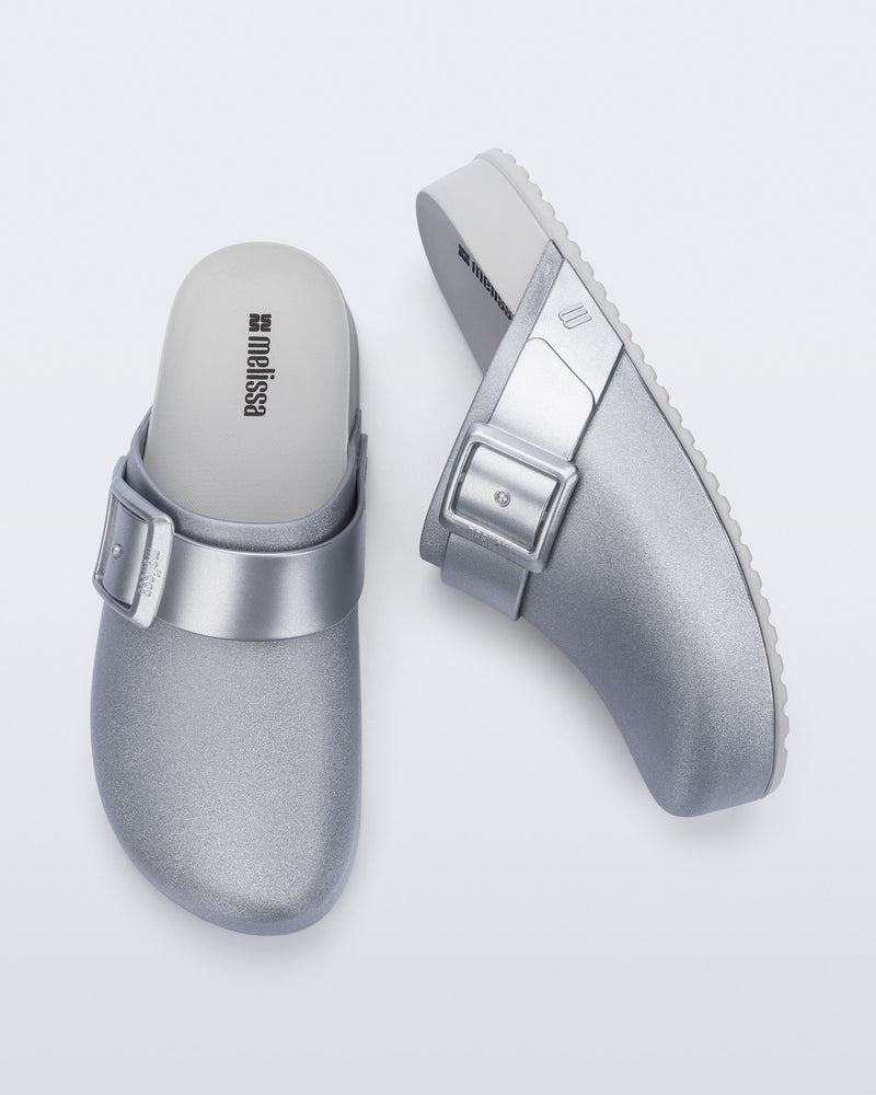 Side and top view of a pair of silver Cozy Clog with buckle decoration