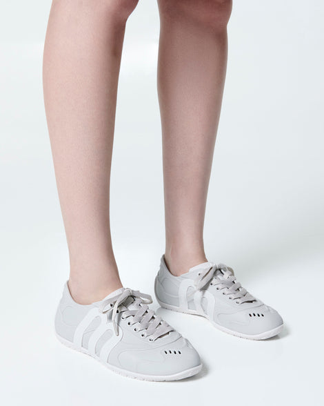 Model's legs wearing a pair of grey Motion sneakers with white colored sole and M monogram