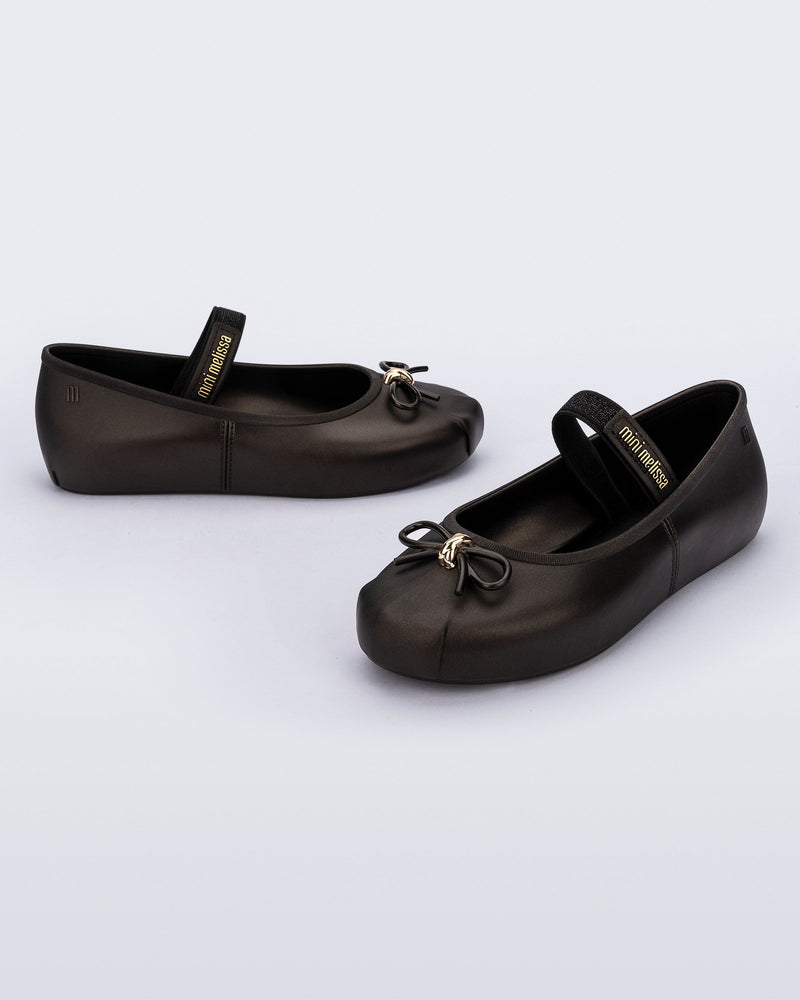 Side and angled view of a pair of metallic black Sophie kids ballerina flats with bow