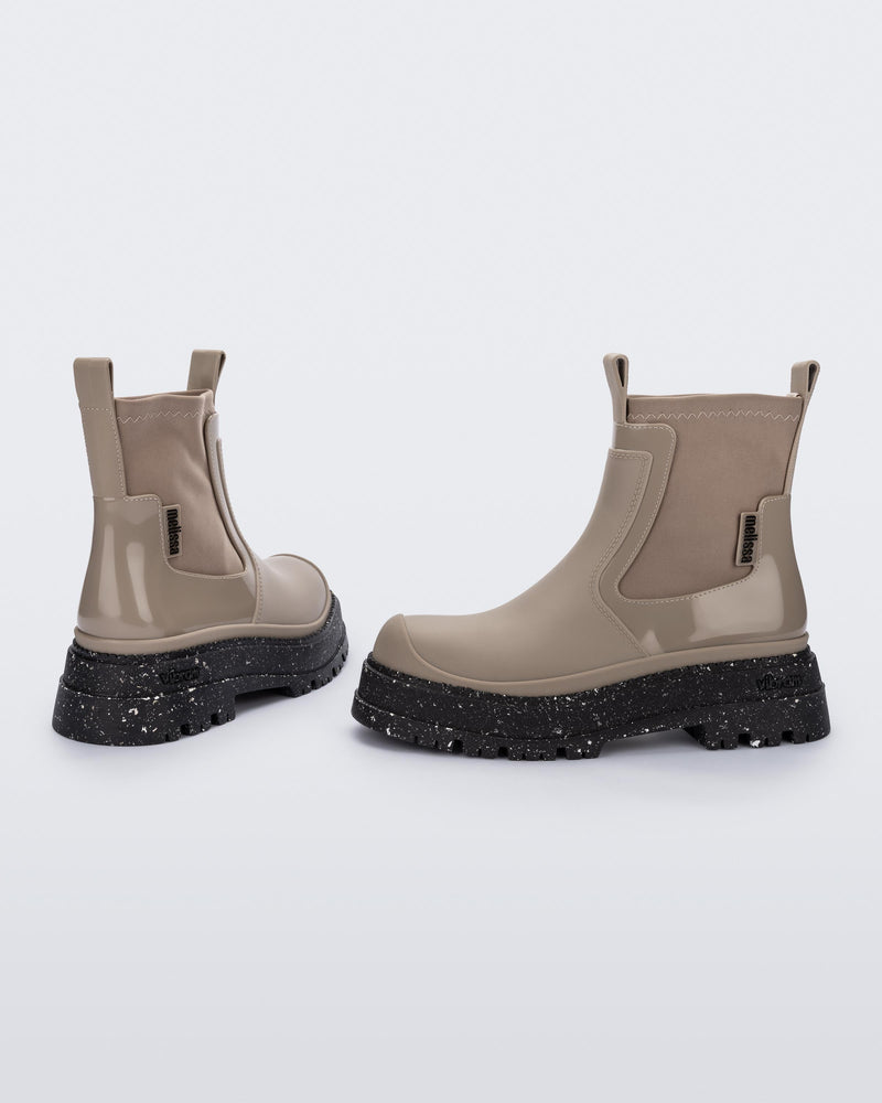 Side and back angled view of a pair of beige Drip Boots with black sole